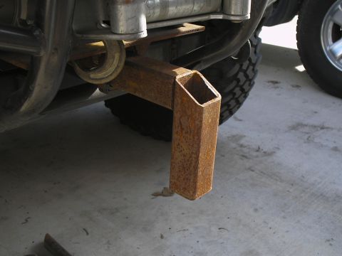 1990 Ford Bronco - Close-up of a rusty tow hitch receiver extension mounted on a vehicle's undercarriage.