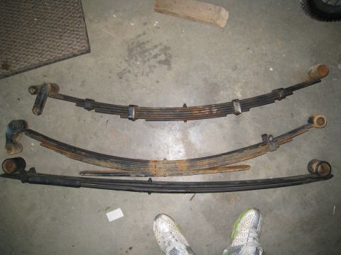 1996 Ford Bronco - Three sets of leaf springs are displayed on a garage floor.