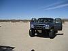 1986 Ford Bronco - A dark blue pickup truck sits in a vast, sandy landscape with its doors ajar.
