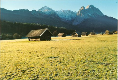 2003 Jeep TJ - Wooden huts are scattered across a grassy field with a mountain range in the background.