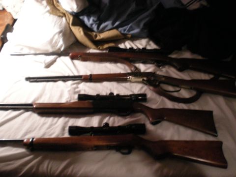 1993 Ford Bronco - Multiple rifles are arranged on a bed, some equipped with scopes.