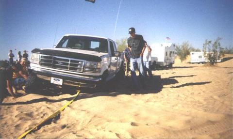 1992 Ford F-150 - A 1992 Ford F-150 truck is being pulled out of the sand with a tow strap, with campers in the background.