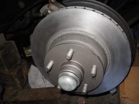 1968 Shelby GT500 - A close-up view of a vehicle's front brake rotor and hub assembly, showing the lug studs and dust cap.