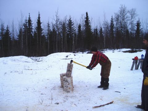 2000 Ford E350 - A man in a red plaid shirt chops wood in a snow-covered area with trees in the background.