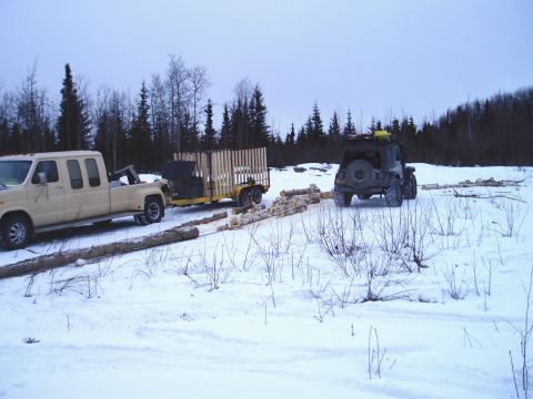 2000 Ford E350 - Two vehicles and a trailer are parked in a snowy field, with logs scattered around.