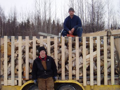2000 Ford E350 - Two men stand next to a trailer filled with firewood, with a chainsaw on top.