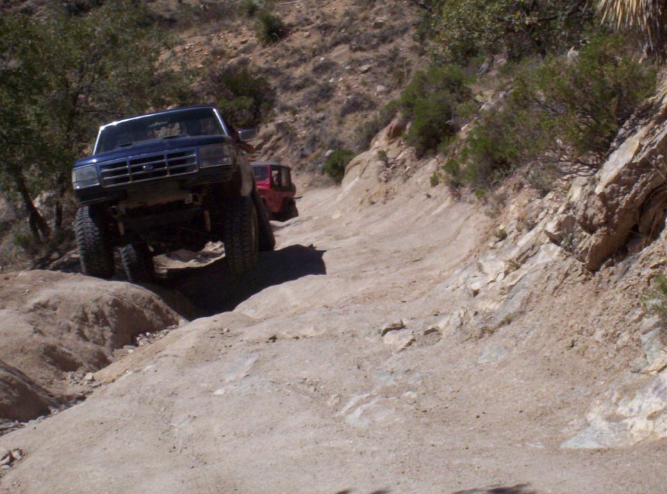 1992 Ford F-150 and another off-road truck climbing a steep dirt trail