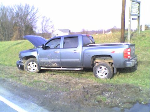 1990 Ford Bronco - A blue pickup truck is parked off the side of the road with its hood open.