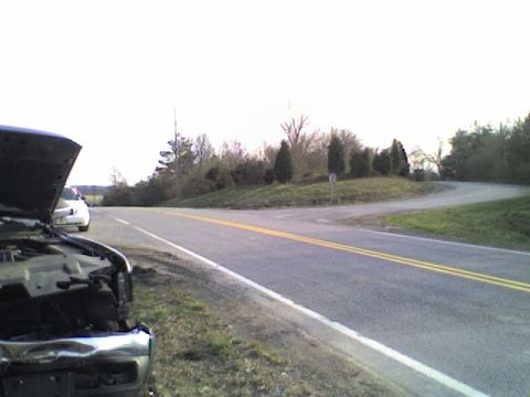 1990 Ford Bronco - A dark vehicle sits on the roadside with its hood open, a white car visible in the distance.