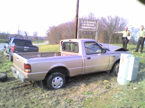 1990 Ford Bronco - A tan pickup truck sits damaged off the side of the road near a St. Stephen's Lutheran Church sign, with another truck and two individuals…