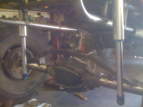 1966 Ford Bronco - Close-up of the custom suspension and drivetrain of a modified off-road vehicle.