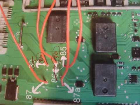 2003 Ford Crown Victoria - Close-up of a circuit board with red wires connected and handwritten annotations indicating electrical terminals.
