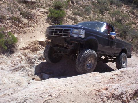 1992 Ford F-150 - Black 1992 Ford F-150 truck navigating a challenging off-road trail with large rocks.