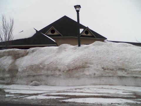 2000 Chevrolet Tahoe - A large snowdrift obscures the lower portion of a building, with a street lamp visible against an overcast sky.