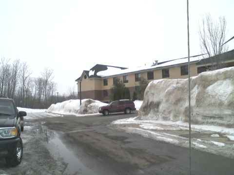 2000 Chevrolet Tahoe - A maroon SUV is parked on a wet road surrounded by snow piles in front of a building.