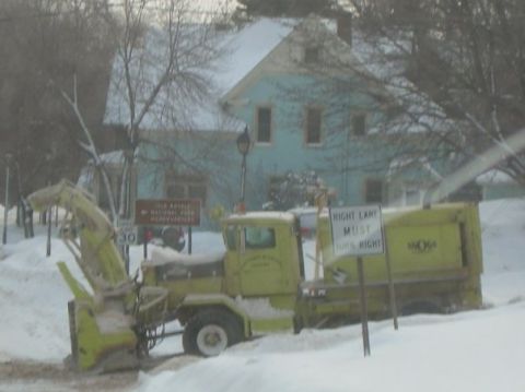 2000 Chevrolet Tahoe - A snow blower truck is parked on a snow-covered road next to a house, with traffic signs visible.