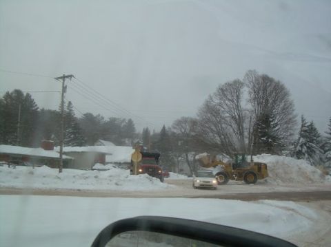 2000 Chevrolet Tahoe - A white car navigates a snowy road past a snowplow and a front-end loader clearing a large pile of snow.