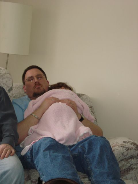 2000 Ford Crown Victoria - A man rests with a sleeping child on his lap, both covered by a soft pink blanket.