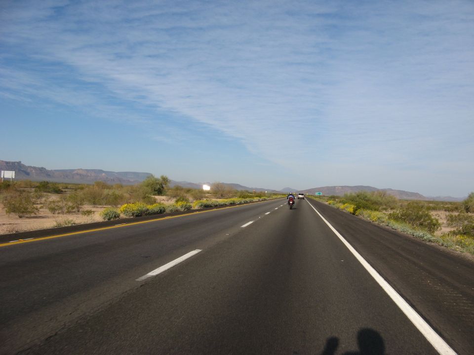 Motorcycle riding on a highway through a desert landscape