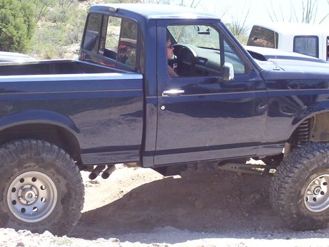 1992 Ford F-150 - Side view of a lifted 1992 Ford F-150 pickup truck with large off-road tires.