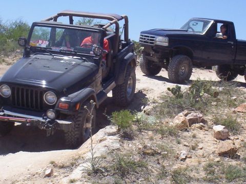 1992 Ford F-150 - Two off-road vehicles, a 1992 Ford F-150 and a Jeep Wrangler, navigate a rocky trail under a clear blue sky.
