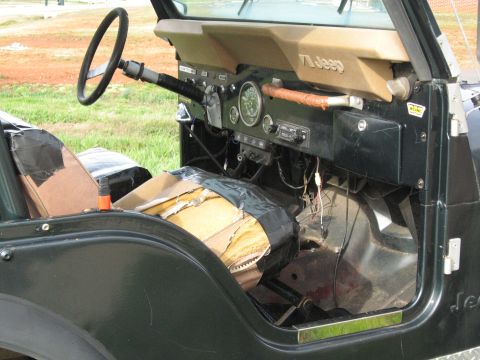 1988 Ford Bronco - Interior of a Jeep CJ, likely from the 1970s, with worn seats and exposed wiring.