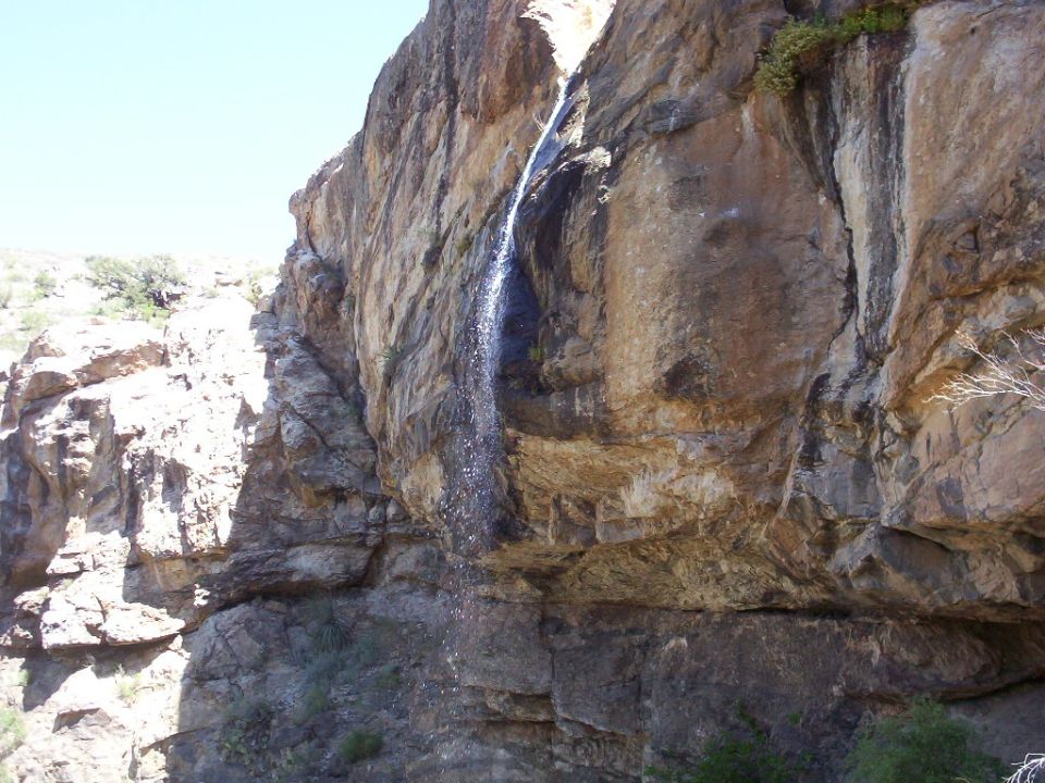 Waterfall cascading down a rocky cliff face with "SUPERMOTORS" text at the bottom right