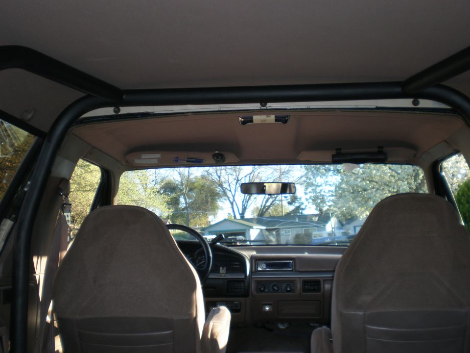 Interior view of a 1993 Ford Bronco showing front seats, dashboard, and custom roll bar