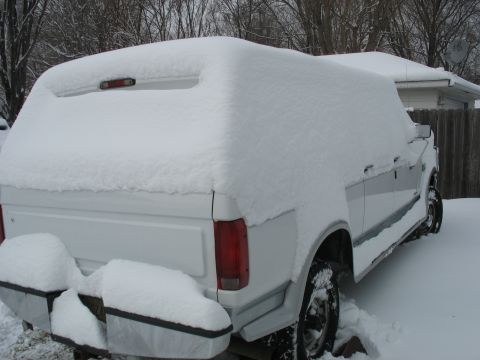 1995 Ford C-350 (Centurion Conversions) - A white pickup truck is covered in snow, with trees and a house visible in the background.