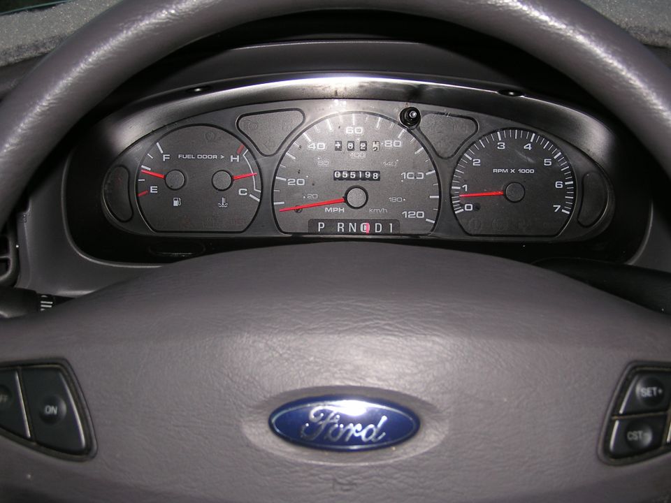 Ford gauge cluster through gray steering wheel, odometer reading 055198 miles