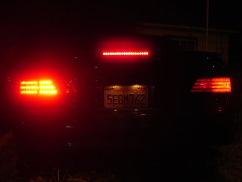 1993 Ford Taurus - The rear of a car is visible at night, with its tail lights illuminated and a California license plate.