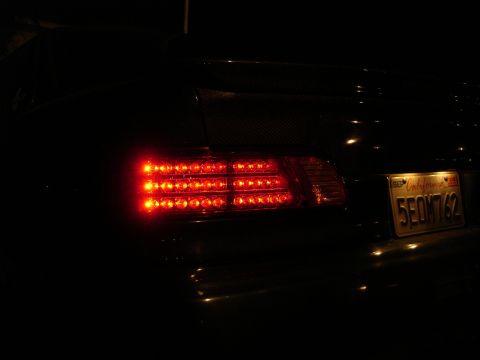 1993 Ford Taurus - The rear of a car is shown at night, focusing on the illuminated LED tail lights and a license plate.