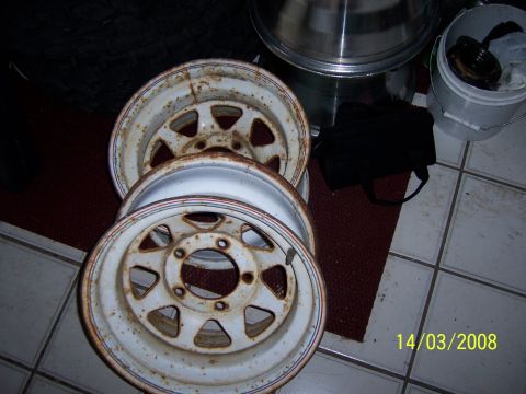 1991 Ford Bronco - Stack of three rusty steel wheels, likely for an older truck or SUV.