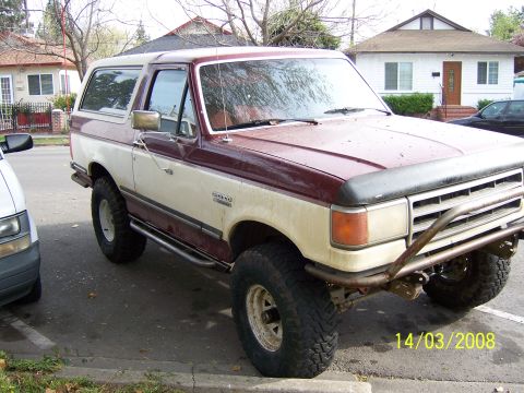 1991 Ford Bronco - This Ford Bronco features a two-tone paint scheme and a custom front bumper, parked on a residential street.