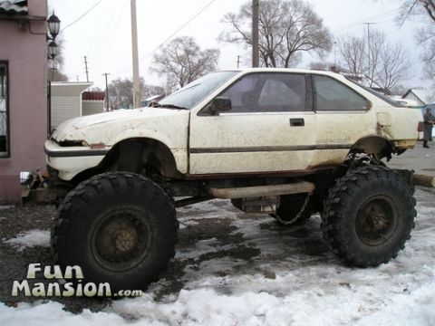 1980 Ford Bronco - This heavily modified car sits on a custom frame with extremely large tires, appearing to be a homemade off-road vehicle.