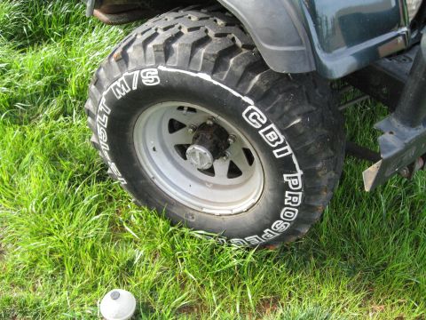 1988 Ford Bronco - A close-up view of a tire and wheel on a vehicle parked on grass.