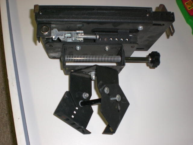 Close-up of a black mechanical part with springs, clamps, and a threaded rod