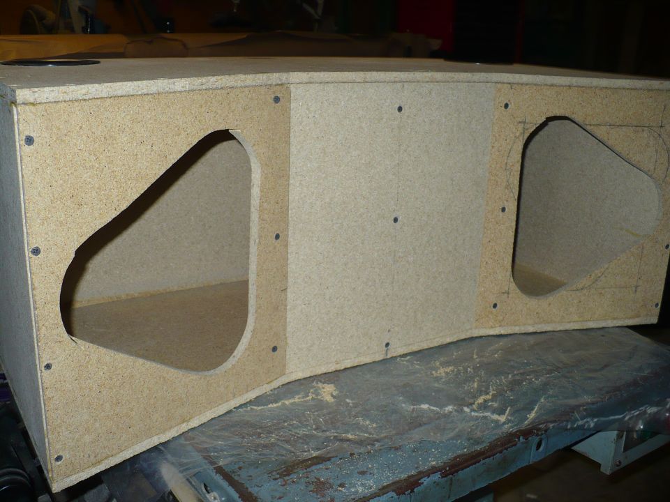 unfinished speaker box with two large cutouts, made of particle board
