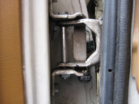 1980 Ford Bronco - Close-up of a vehicle's door hinge assembly, showing mechanical components and interior trim.