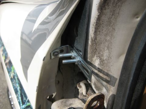 1980 Ford Bronco - Close-up view of a metal bracket and bolts installed in a vehicle's door jamb.