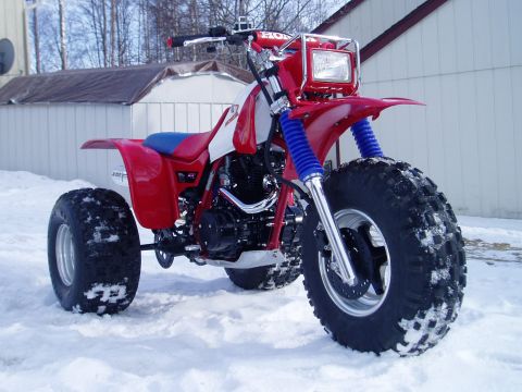 2000 Ford E350 - A red Honda three-wheeler ATV sits in the snow, showing its front tire and handlebars.