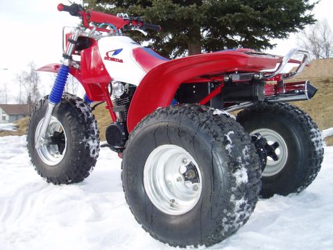 2000 Ford E350 - A red and white three-wheeled ATV sits in the snow, showing its large tires and Honda branding.