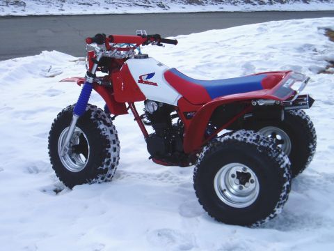 2000 Ford E350 - A red and white three-wheeled ATV is parked in the snow, showing its front and side profile.
