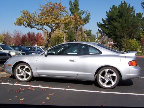 1996 Ford Probe - Side view of a silver coupe parked in a lot with autumn leaves on the ground.