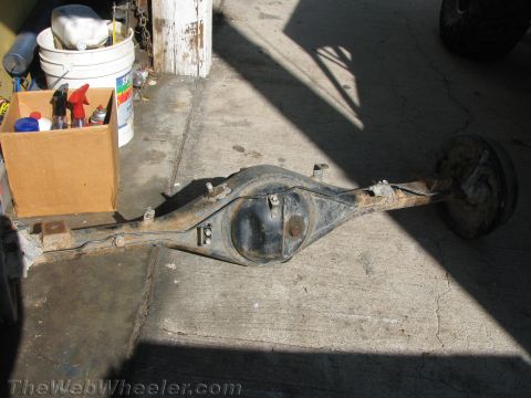 1987 Suzuki Samurai - This is a rusted rear axle assembly, likely from an older vehicle, resting on a concrete surface.
