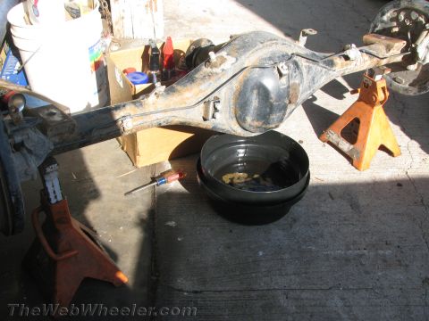 1987 Suzuki Samurai - A disassembled rear axle assembly rests on jack stands, with a drain pan and tools nearby.
