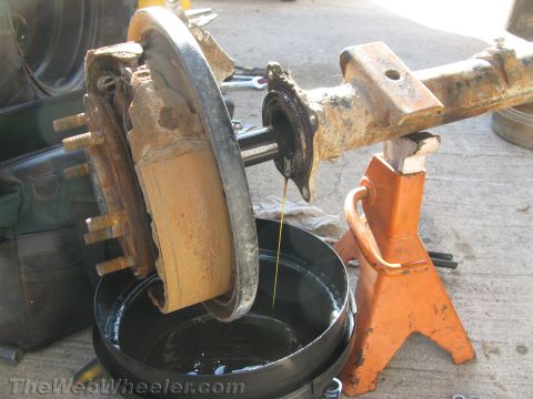 1987 Suzuki Samurai - Axle assembly with brake drum is shown draining fluid into a bucket.