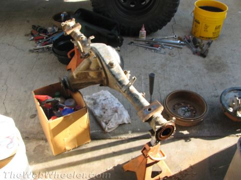 1987 Suzuki Samurai - A disassembled vehicle axle assembly rests on orange jack stands, surrounded by tools and brake components.