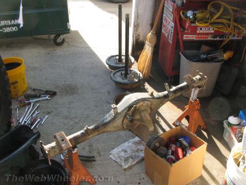 1987 Suzuki Samurai - A disassembled vehicle axle assembly is shown supported by jack stands in a workshop setting.