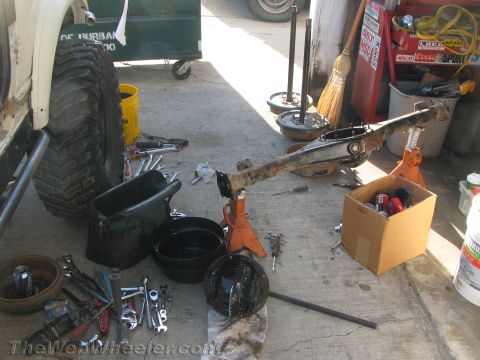 1987 Suzuki Samurai - A vehicle axle is disassembled and laid out with various tools and parts on a concrete surface.